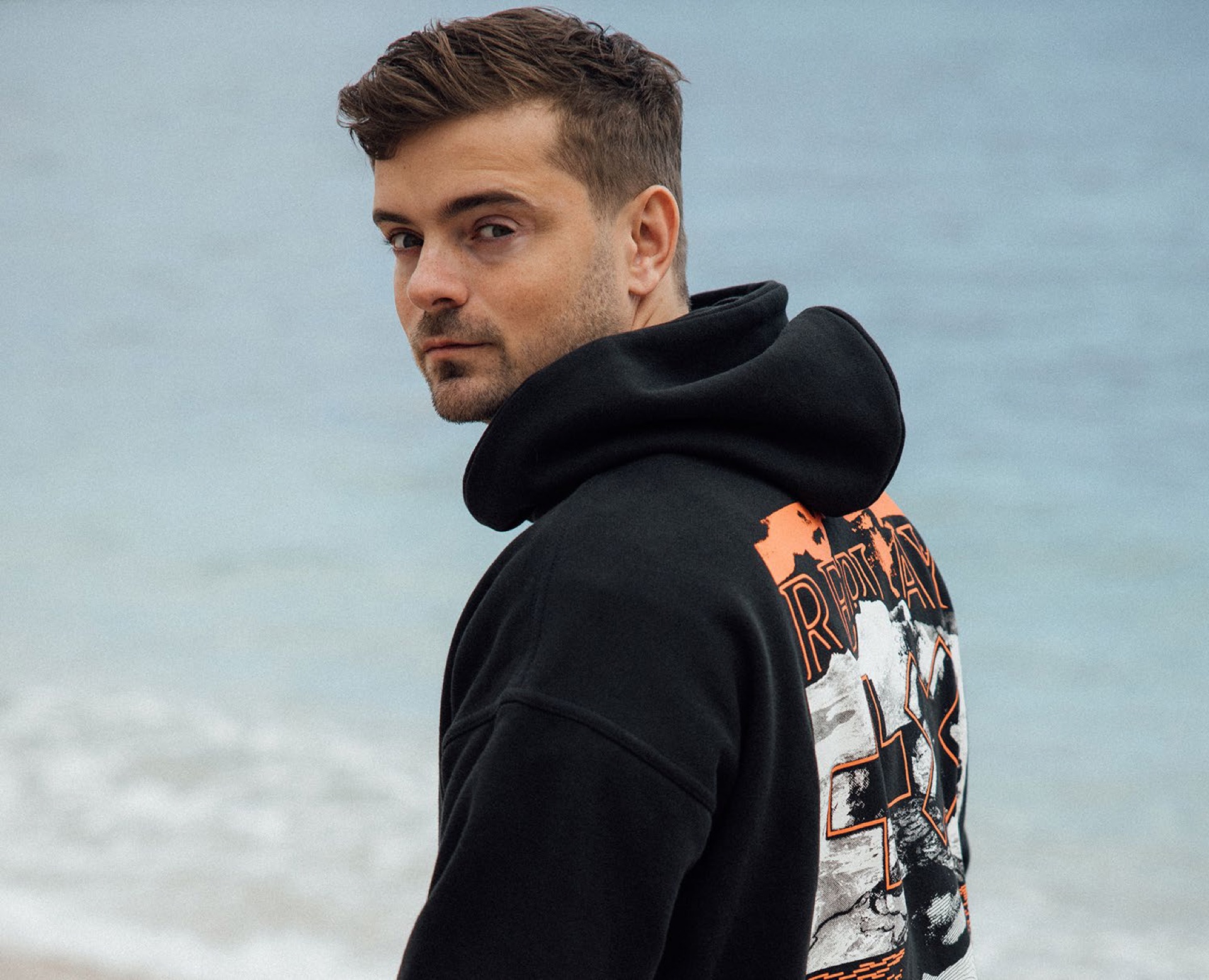 Martin Garrix wearing REPLAY hoodie by the sea
